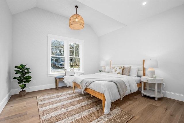 bedroom with lofted ceiling, light wood-type flooring, and baseboards