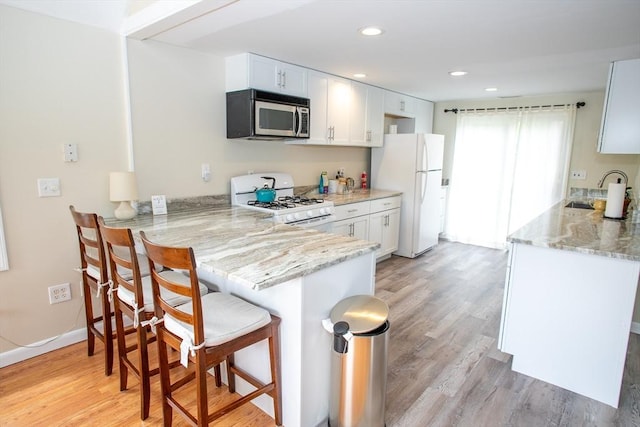 22 Everton Ave, Worcester, MA 01604 - kitchen featuring white appliances, a sink, a kitchen bar, light stone countertops, and light wood finished floors
