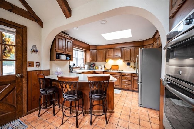 203 Pond St, Weymouth, MA 02190 - kitchen featuring appliances with stainless steel finishes, a peninsula, arched walkways, a skylight, and wainscoting