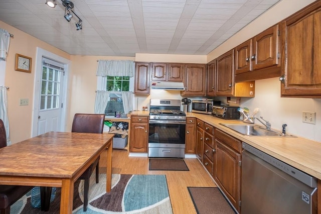 203 Pond St, Weymouth, MA 02190 - kitchen featuring stainless steel appliances, a sink, light wood-type flooring, under cabinet range hood, and light countertops