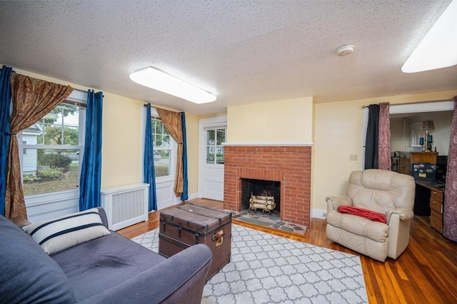 203 Pond St, Weymouth, MA 02190 - living area with radiator heating unit, wood finished floors, a textured ceiling, a fireplace, and baseboards