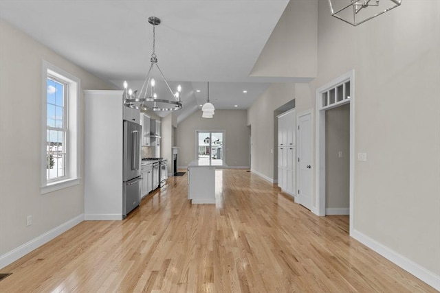 kitchen with light hardwood / wood-style floors, a kitchen island, decorative light fixtures, vaulted ceiling, and high end refrigerator