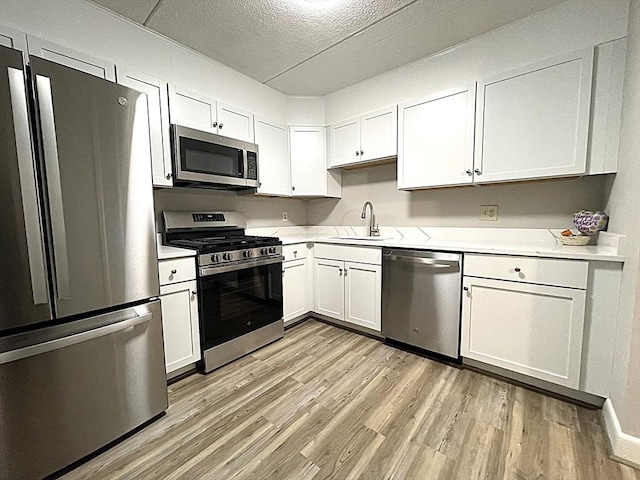 1550 Worcester Rd Unit 524, Framingham, MA 01702 - kitchen featuring appliances with stainless steel finishes, a sink, light wood-style flooring, light countertops, and a textured ceiling