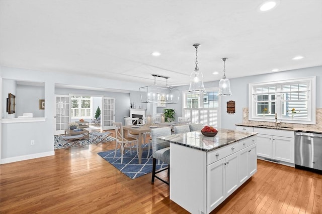 21 Bearberry Path Unit 0, Plymouth, MA 02360 - kitchen featuring stainless steel dishwasher, a sink, open floor plan, a center island, and light wood finished floors