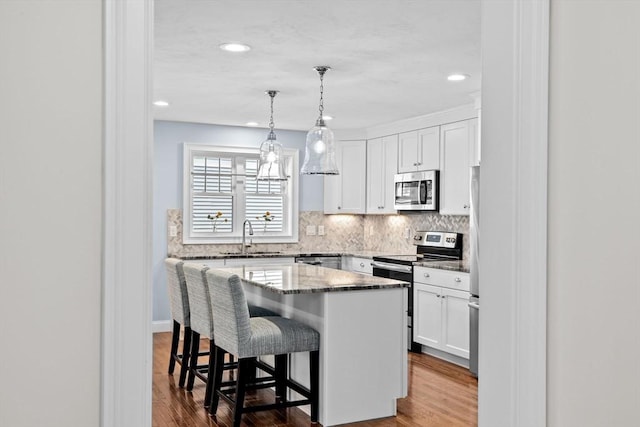 21 Bearberry Path Unit 0, Plymouth, MA 02360 - kitchen with stainless steel appliances, a sink, white cabinetry, a kitchen bar, and decorative backsplash