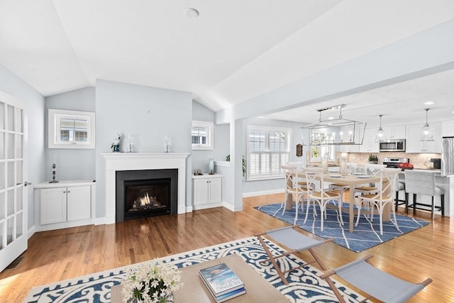 21 Bearberry Path Unit 0, Plymouth, MA 02360 - living area with light wood-style floors, vaulted ceiling, a warm lit fireplace, and baseboards