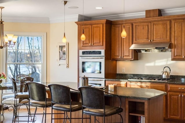 kitchen featuring pendant lighting, a center island, a notable chandelier, stainless steel appliances, and crown molding