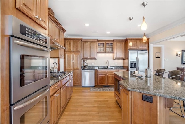 kitchen with a breakfast bar, sink, a center island, hanging light fixtures, and stainless steel appliances