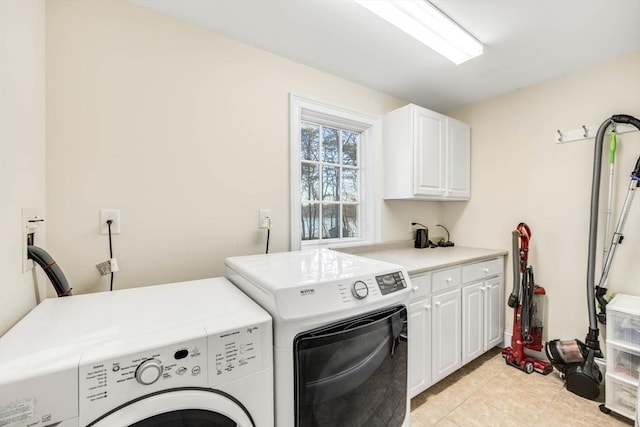 washroom featuring light tile patterned floors, washing machine and dryer, and cabinets