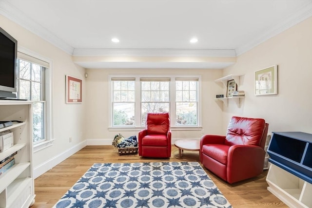 living area featuring crown molding and light hardwood / wood-style floors