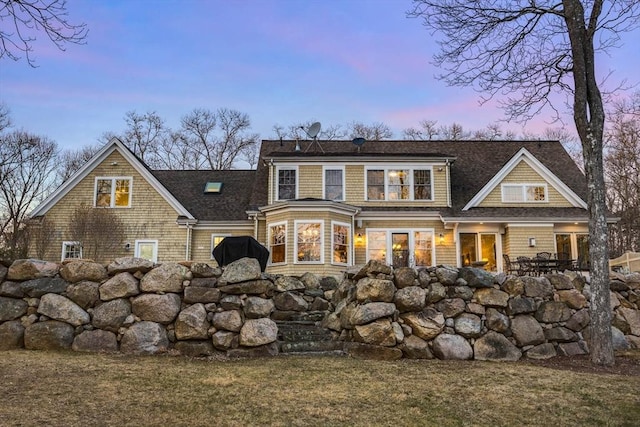 back house at dusk featuring a yard