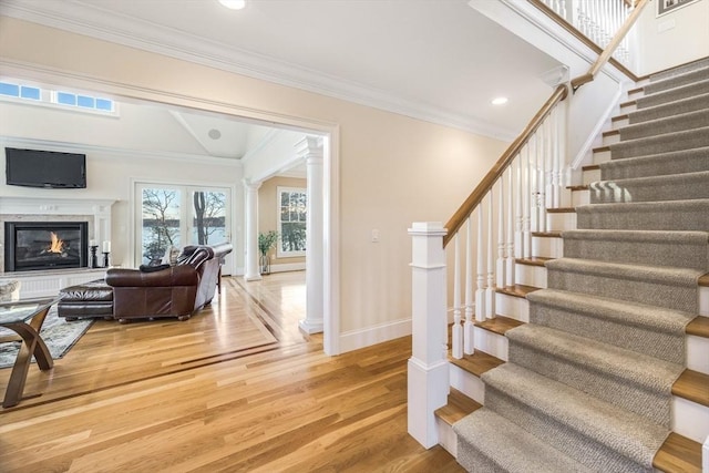 stairs featuring crown molding, wood-type flooring, and decorative columns