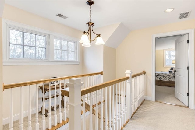 hallway featuring light colored carpet and a notable chandelier