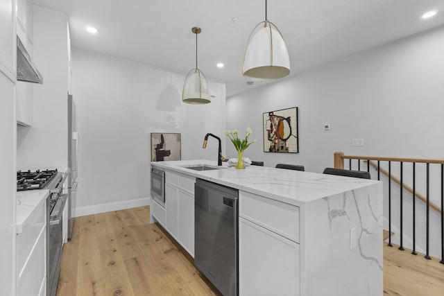 kitchen with an island with sink, hanging light fixtures, sink, white cabinetry, and appliances with stainless steel finishes