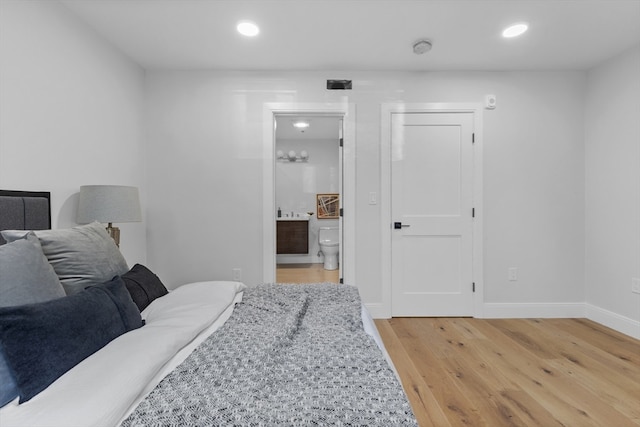 bedroom with hardwood / wood-style floors and ensuite bathroom