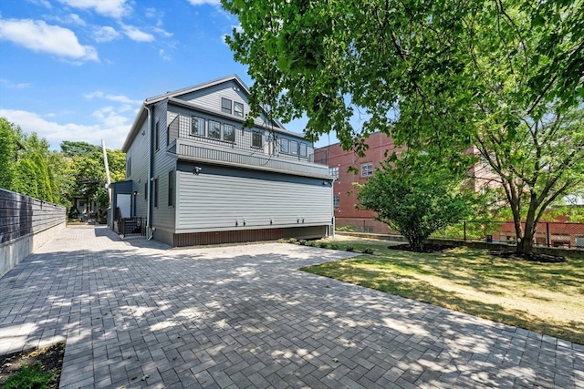 exterior space featuring a patio, a lawn, and a balcony