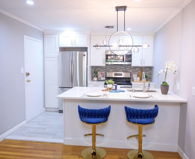 12 Riverside St Unit 1-3, Watertown, MA 02472 - kitchen with appliances with stainless steel finishes, white cabinetry, a breakfast bar area, backsplash, and pendant lighting