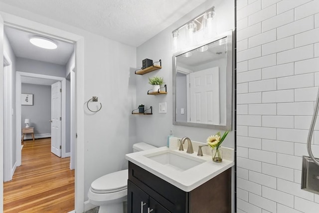 12 Riverside St Unit 1-3, Watertown, MA 02472 - bathroom featuring toilet, wood finished floors, vanity, baseboards, and a textured ceiling
