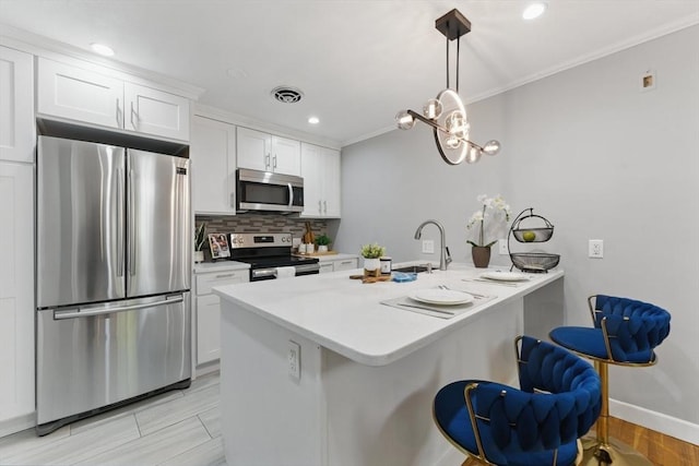 12 Riverside St Unit 1-3, Watertown, MA 02472 - kitchen with appliances with stainless steel finishes, crown molding, white cabinetry, a sink, and a peninsula