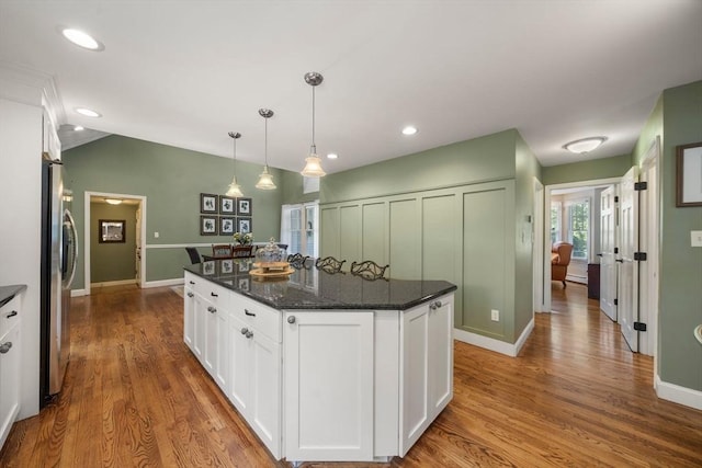 1 Liberty Ln, North Reading, MA 01864 - kitchen with stainless steel fridge, white cabinets, wood finished floors, dark stone counters, and lofted ceiling