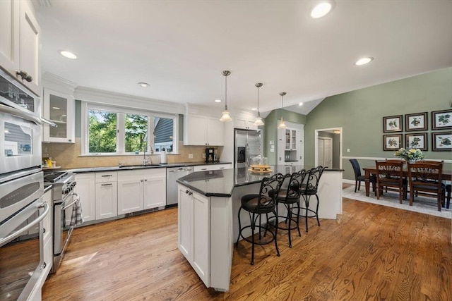 1 Liberty Ln, North Reading, MA 01864 - kitchen with appliances with stainless steel finishes, a breakfast bar, a center island, white cabinetry, and backsplash