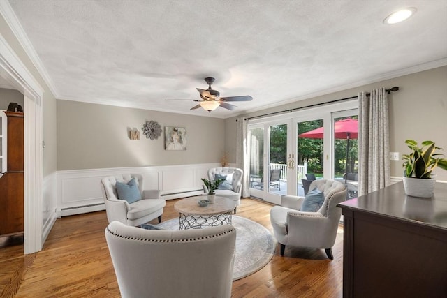 1 Liberty Ln, North Reading, MA 01864 - living area featuring a baseboard heating unit, crown molding, a wainscoted wall, a ceiling fan, and wood finished floors