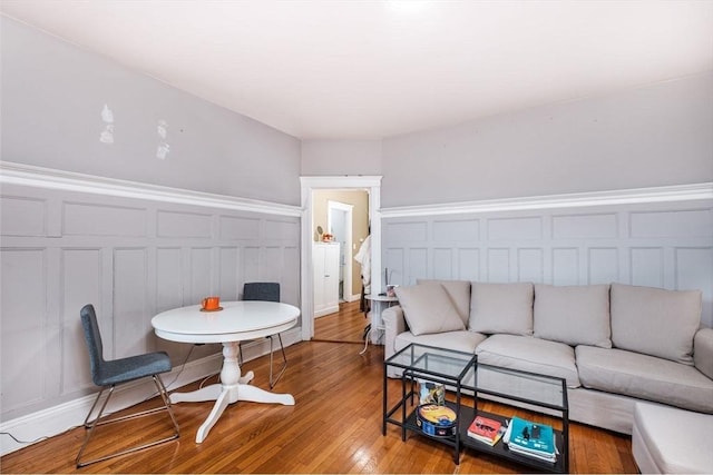 living room with a decorative wall, wood finished floors, and a wainscoted wall