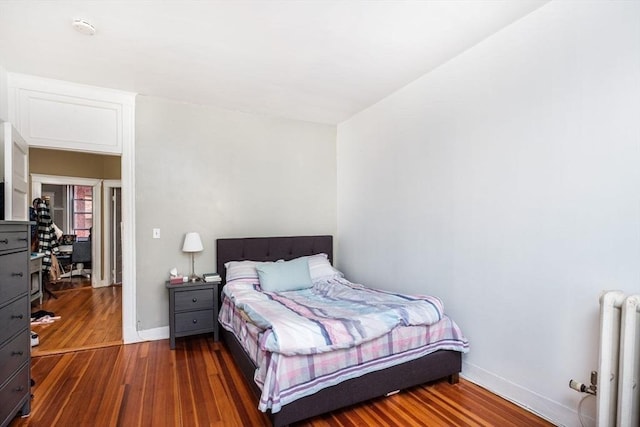 bedroom featuring dark wood-type flooring, radiator, and baseboards