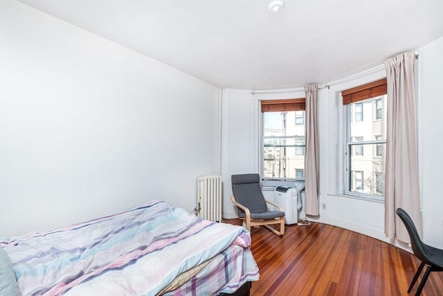 bedroom with radiator heating unit and wood finished floors