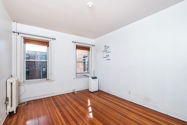 spare room with hardwood / wood-style floors, radiator, and baseboards