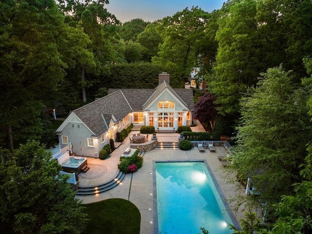 pool featuring an exterior structure, an outdoor structure, a patio, and an in ground hot tub