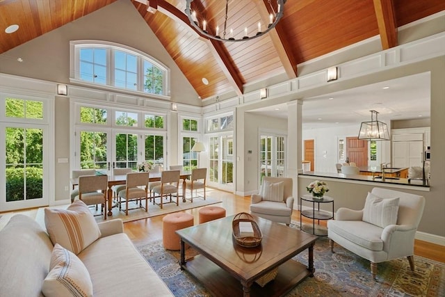 sunroom with lofted ceiling with beams, wooden ceiling, a notable chandelier, and french doors