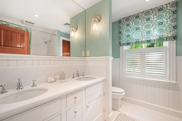 bathroom featuring wainscoting, a sink, visible vents, and toilet