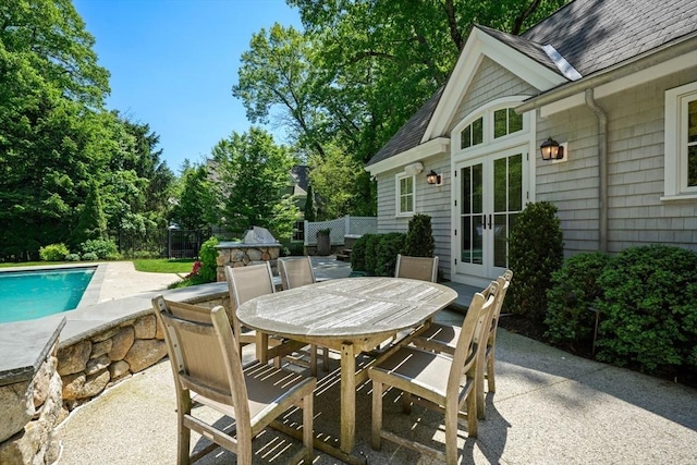 view of patio with french doors, outdoor dining space, fence, and an outdoor pool