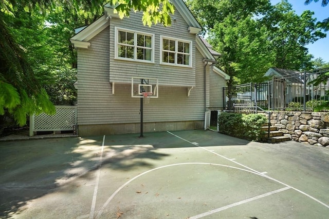 view of basketball court featuring basketball hoop and fence