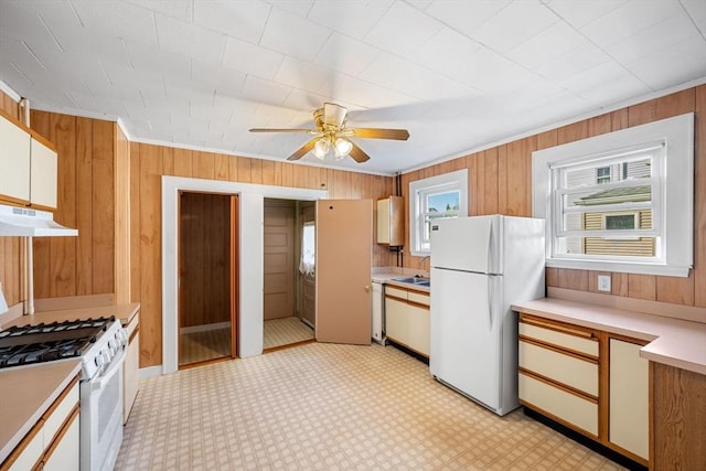 kitchen featuring white appliances, ceiling fan, ornamental molding, white cabinets, and wood walls