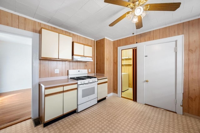 kitchen with crown molding, wood walls, and gas range gas stove