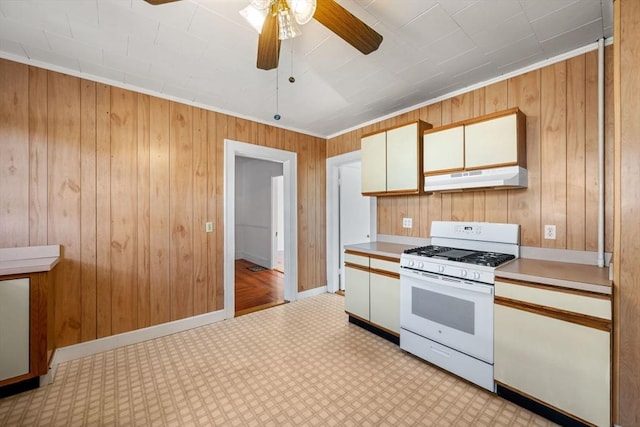 kitchen featuring crown molding, light colored carpet, gas range gas stove, and wood walls