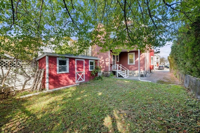 rear view of house with a yard and a storage unit