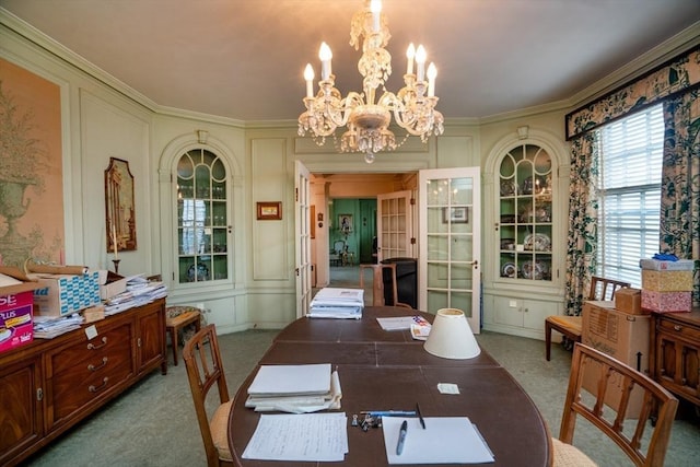 carpeted dining area with an inviting chandelier, crown molding, and a decorative wall