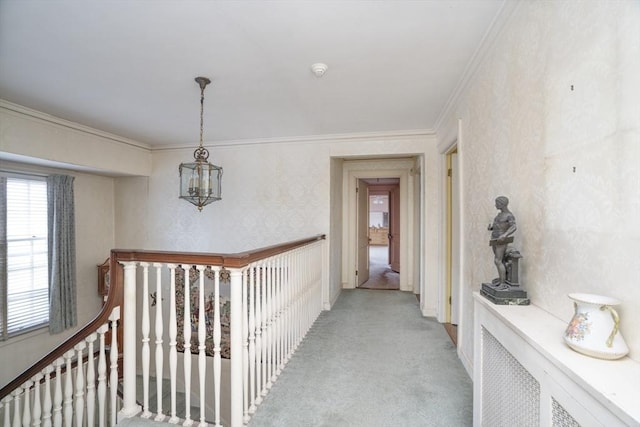 hallway with a notable chandelier, an upstairs landing, light colored carpet, and ornamental molding