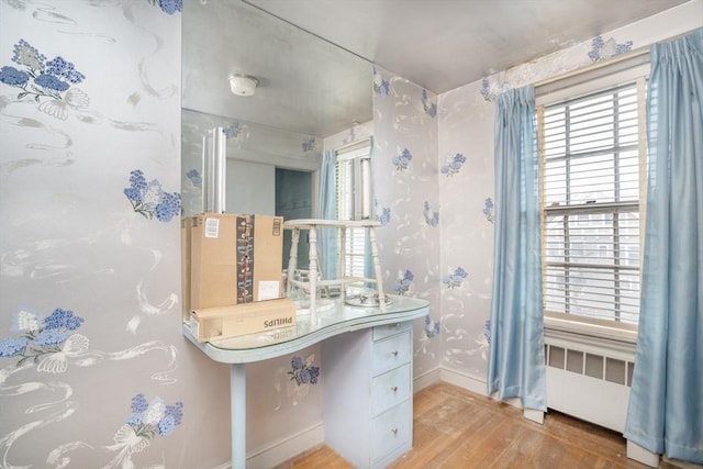 bathroom with radiator, wood finished floors, and baseboards