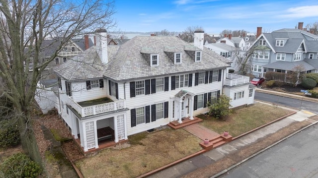 view of front of home featuring a residential view, a chimney, and a balcony