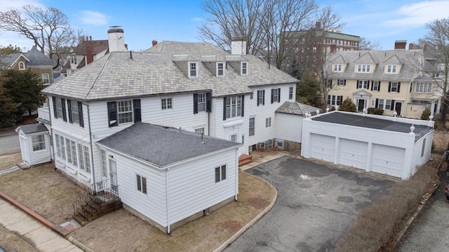 view of front of house with a detached garage, an outdoor structure, and a chimney