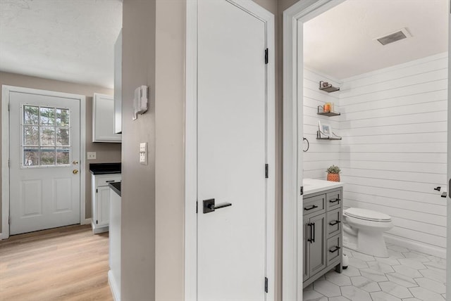 47 Plantation Rd Unit 47, Oxford, MA 01540 - bathroom featuring visible vents, wooden walls, toilet, wood finished floors, and vanity
