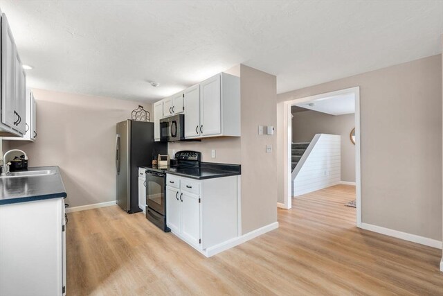 47 Plantation Rd Unit 47, Oxford, MA 01540 - kitchen featuring black / electric stove, a sink, dark countertops, freestanding refrigerator, and light wood-style flooring