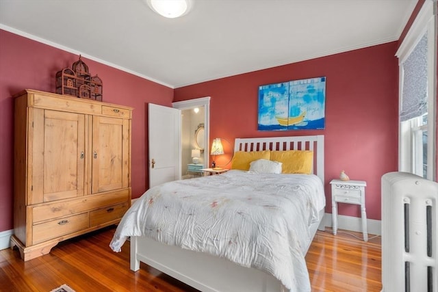 bedroom featuring radiator, crown molding, baseboards, and wood finished floors