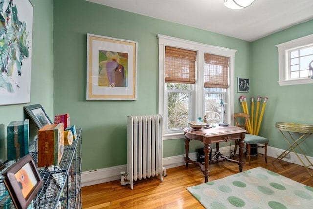 sitting room with baseboards, radiator heating unit, and wood finished floors