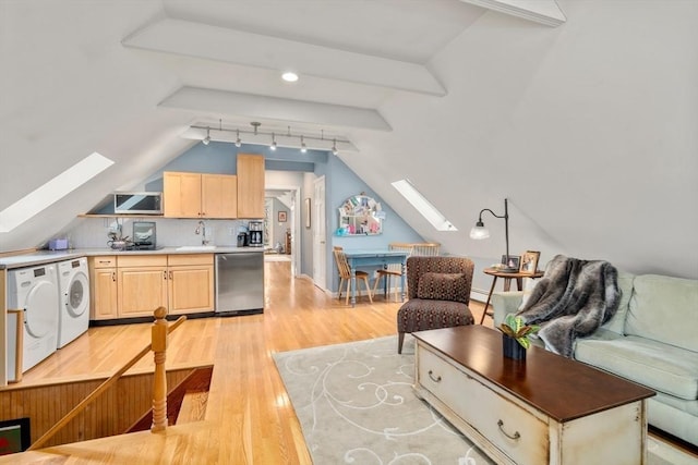 kitchen with washer and clothes dryer, dishwasher, light wood-style flooring, open floor plan, and light brown cabinets