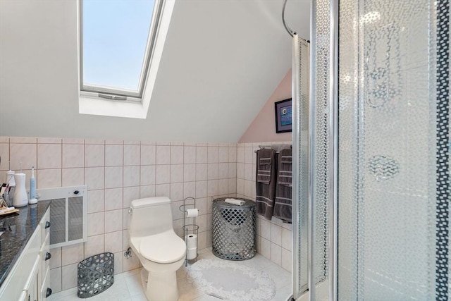 bathroom with tile walls, toilet, lofted ceiling with skylight, a shower stall, and vanity